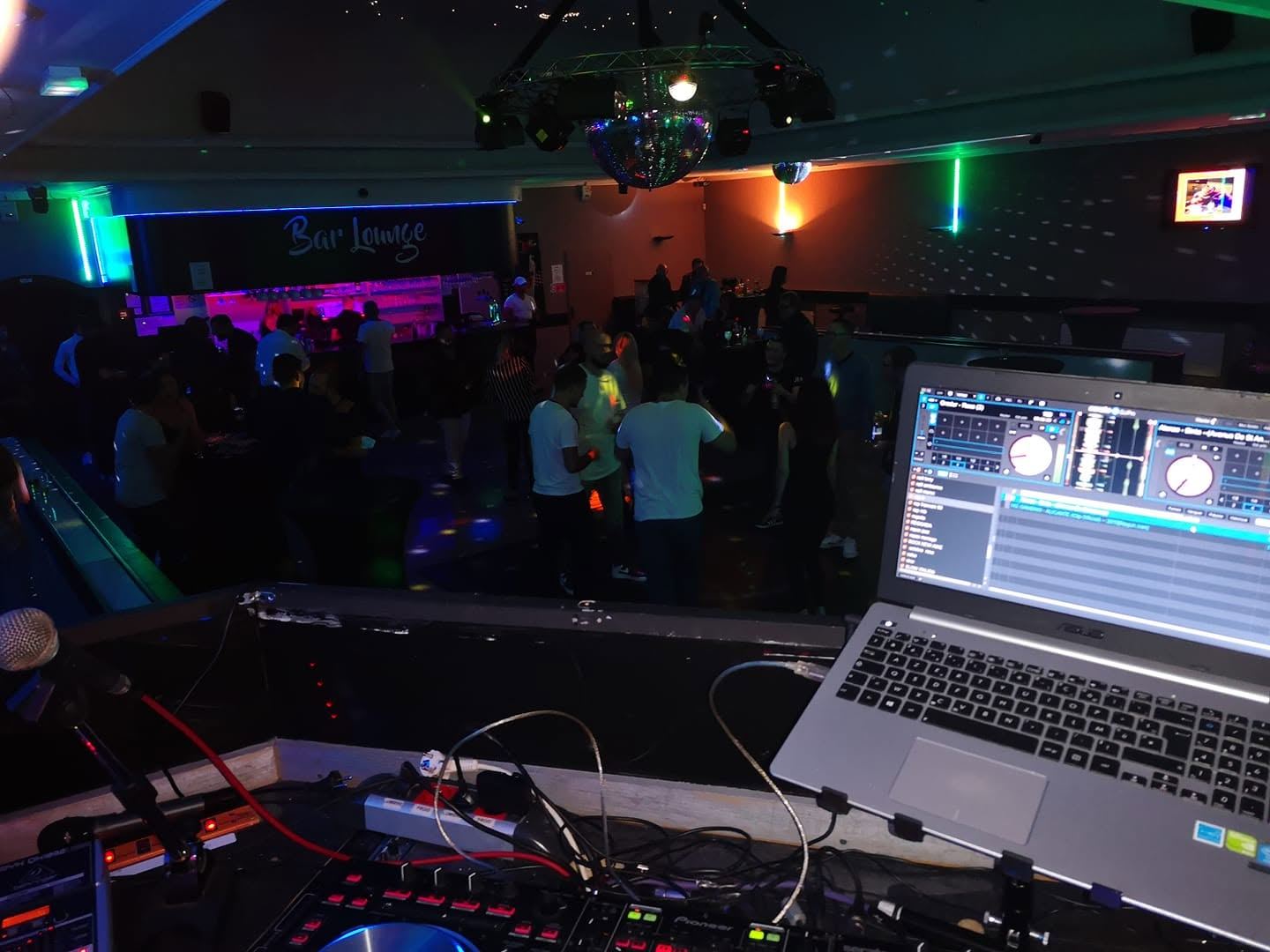 Les platines et l'ordinateur de Tony face à la piste d'un bar, sous la boule à facettes