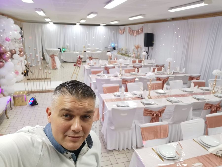 Tony dans une salle de réception décorée en blanc et rose, les tables dressées